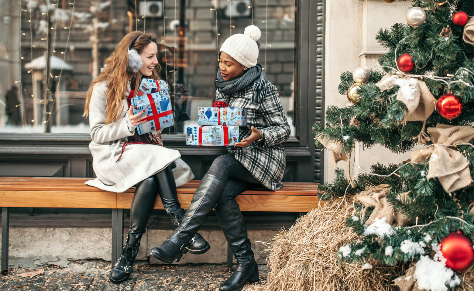 Two women exchange gifts in front of a store.